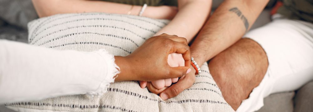 Counselor grabbing hands of patients in supportive way over pillow